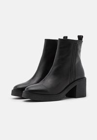 Black leather ankle boots with a pointed toe, elastic side panels, and textured black block heels. Smooth finish with vertical stitching detail.