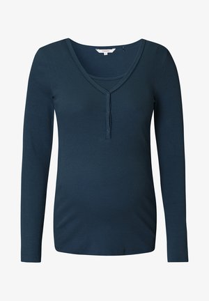 Zwangertop in diep teal, geribbelde textuur, lange mouwen, V-hals met knoopdetail en een aansluitend ontwerp voor comfort.
