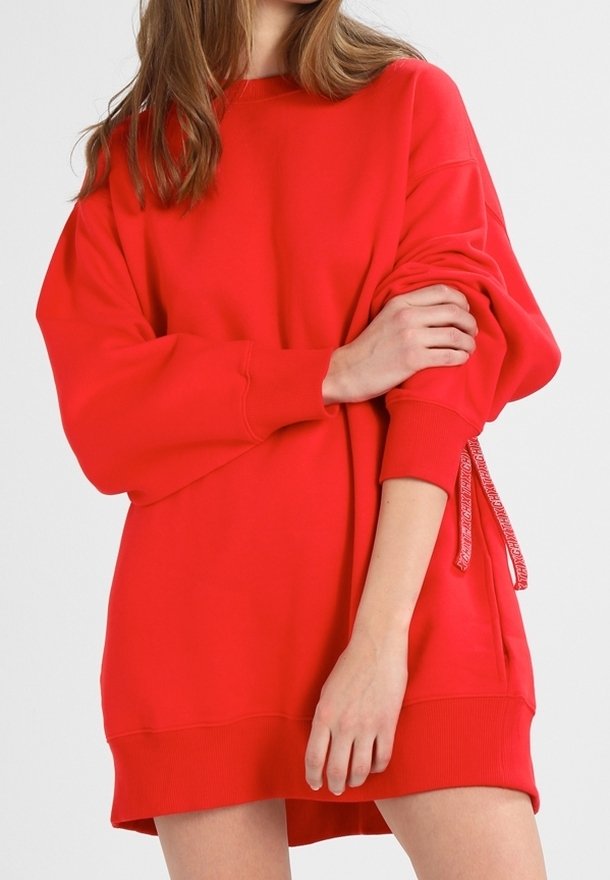 Sweatshirt rouge surdimensionné avec un col rond, des manches longues et un détail à cordon de serrage sur un côté ; fabriqué en tissu doux et texturé.