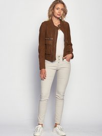Bruine suede bomberjack met een ronde kraag, voorzien van twee voorkruiden en zilveren ritsen, gecombineerd met lichtbeige strakke broek en witte sneakers.