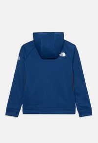 Sweatshirt azul marinho com um bolso frontal, capuz ajustável e logótipo no ombro esquerdo. O tecido tem uma textura suave e punhos canelados.