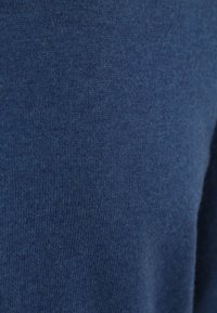 Blauwe gebreide stof met een zachte textuur. Toont een close-up van een gladde, evenweven structuur, waardoor de diepte van de kleur en de materiaalkwaliteit wordt benadrukt.