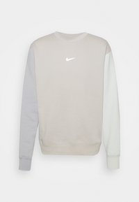 Světlě šedá mikina s kulatým výstřihem, třemi rukávy v barevných blocích a malým bílým logem Nike na hrudi.