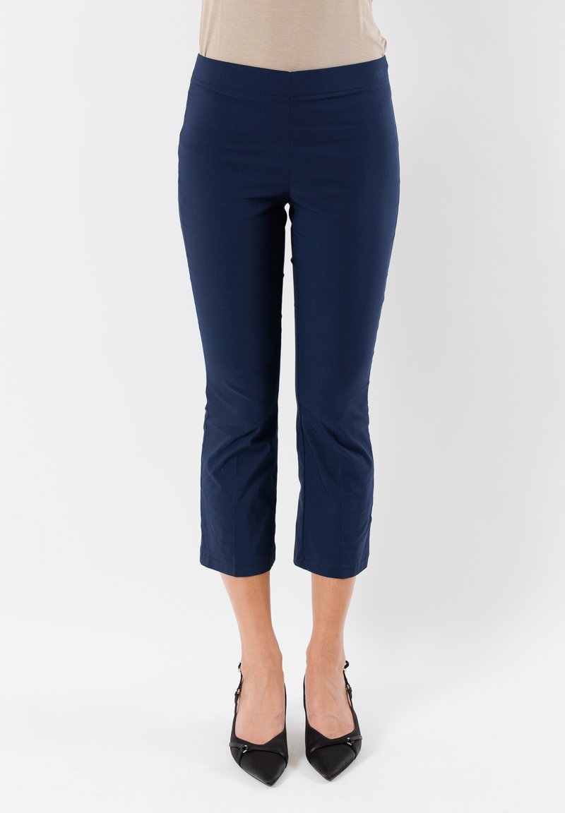 Pantaloni blu navy a vita alta con una superficie liscia e una fascia elastica, caratterizzati da una vestibilità sartoriale e che terminano poco sopra la caviglia.