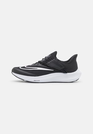 Chaussure de sport noire avec une tige texturée, fermeture lacée et un logo swoosh blanc proéminent. Dispose d'une semelle intermédiaire blanche rembourrée et d'une semelle extérieure en caoutchouc.