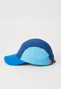 Zila un gaiši zila cepure ar struktūrētu vizieri, izgatavota no viegla auduma, ar mazu Norvēģijas karoga akcentu uz sāna.