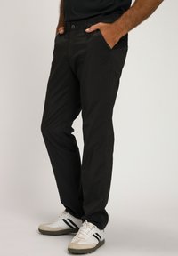 Pantaloni neri realizzati in tessuto leggero, con tasche frontali e vestibilità dritta. Indossati con sneakers bianche, che mettono in risalto una sottile texture.