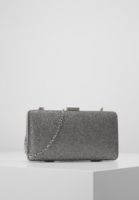 Pochette rectangulaire argentée en tissu texturé, avec une bandoulière chaîne métallique et une fermeture à fermoir. Design compact avec une finition élégante.