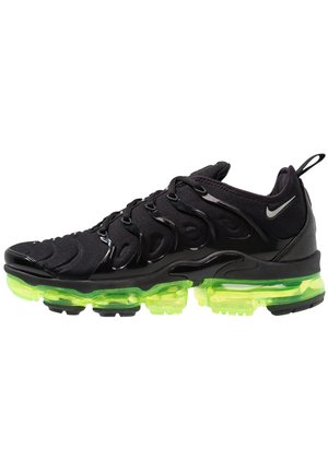 Chaussure de sport noire avec un dessus en tissu texturé, un système de laçage sécurisé et une semelle à coussin d'air vert fluo. Semelle extérieure en caoutchouc noir avec adhérence.
