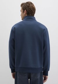 Navyblauer Fleece-Pullover mit hohem Kragen, langen Ärmeln, gerippten Bündchen und Saum, glatter Textur und ohne sichtbare Logos oder Muster.