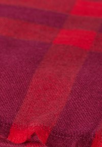 Tejido de cuadros en tonos rojos y morados, con una textura suave, que presenta un patrón tejido de grandes cuadrados, con una mezcla de matices y un ligero brillo.