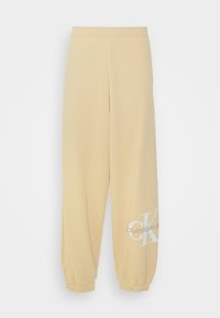 Geel katoenen trainingsbroeken met elastische boorden, voorzien van een witte "Calvin Klein Jeans" logo op één been. Zachte textuur en een losvallend ontwerp.