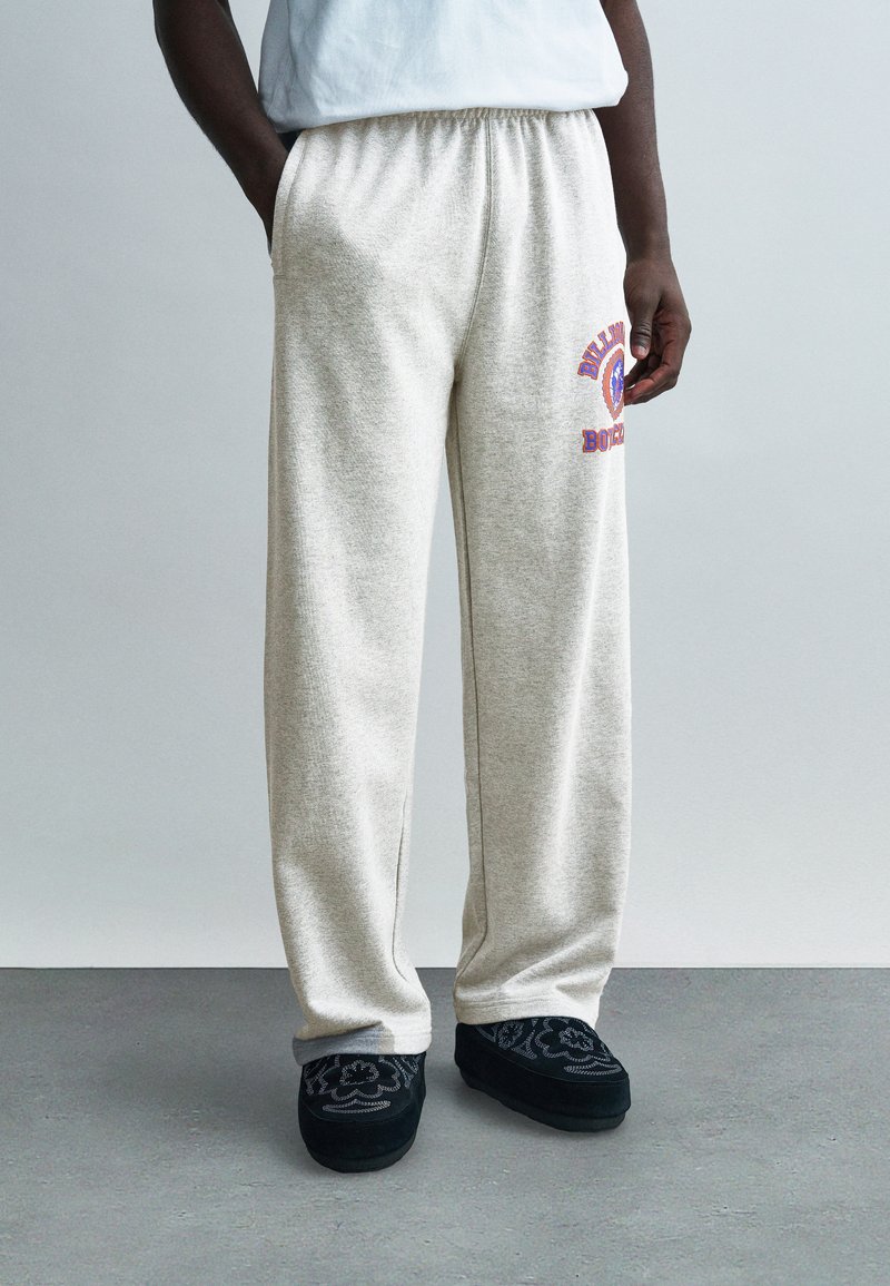 Ανοιχτό γκρι φούτερ παντελόνι με ε λαστική μέση, πλαϊνές τσέπες και σχεδιασμό σε κόκκινο και μπλε, συνδυασμένο με μαύρα κεντημένα λόφερ.