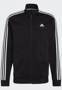 Chaqueta negra con cremallera hecha de tejido suave, con un cuello alto, logo blanco de Adidas en el pecho y tres rayas blancas a lo largo de las mangas.