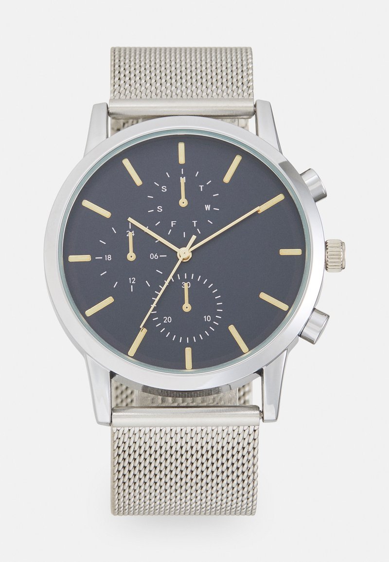 Kronografklokke med sølvmeshrem, grå urskive, gulltimeindekser og tre undermeter. Inkluderer knapper og et hus i rustfritt stål.