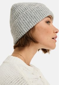 Szary, prążkowany beret wykonany z miękkiego materiału, charakteryzujący się dopasowanym krojem i zawiniętym brzegiem, wyeksponowany na neutralnym tle.