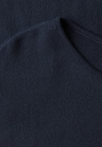 Gros plan d'un tissu tricoté bleu marine foncé avec une texture côtelée visible et un bord plié.