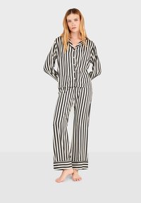 Zwart-wit gestreepte satijnen pyjama set met een overhemd met knopen en wijde broekspijpen, met contrasterende manchetten en een losse pasvorm.