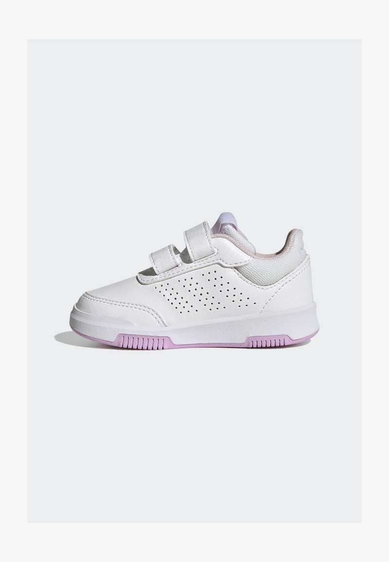Zapatilla blanca con dos cintas de velcro, detalles laterales perforados y un acento lavanda en la suela. Parte superior de cuero liso y malla.
