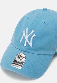 Light blue baseball cap made of cotton, featuring a raised white embroidered NY logo, adjustable strap, and a circular branded tag.