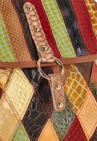 Geantă de mână patchwork multicoloră, cu piele texturată în pătrate galbene, verzi, roșii și negre, având un inel auriu și accente cu mâner neted.