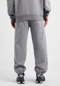 Grijze sweatpants met elastische boorden en een relaxed fit, gecombineerd met zwart en zilver sneakers met een gevoerde zool.