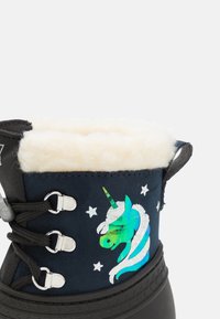 Bota negra de invierno con un forro de piel blanca, que cuenta con un diseño holográfico de unicornio y acentos de estrellas. Incluye ojales reforzados y cordones.