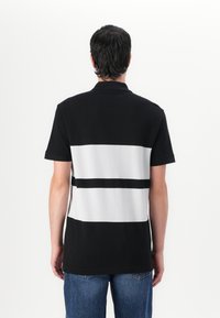 Swarte og kvite stripete polo skjorte med korte ermer og klassisk krage, laget av et glatt stoff med en avslappet passform.