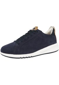 Sneaker in suede blu navy con lacci neri, suola in gomma bianca e dettagli in pelle marrone chiaro vicino al tallone e alla linguetta. Texture liscia e design casual.