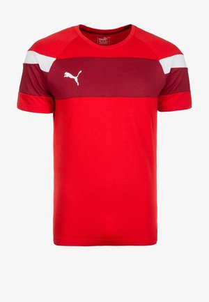 Punainen, lyhythihainen T-paita, jossa on marjapuurovaaleanpunainen vaakaraita ja valkoiset korostukset olkapäillä. Rinnassa on valkoinen Puman logo.