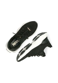 Černé sportovní boty s texturovaným pleteným svrškem, bílou podrážkou, kruhovým vzorkem na podrážce a jemným zlatým akcentem na boku.