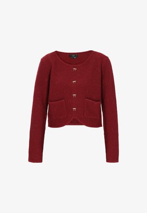 Punane kudumiskardigan pikkade varrukatega, ümmarguse kaelusega, kahe eesmise taskuga ja kuldsete dekoratiivnuppudega. Omab tekstuurset, ribakujulist mustrit.