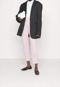 Svart oversized blazer, vit skjorta med krage, rosa byxor och svarta flats. Blazern har en enkel knapp och framficka.