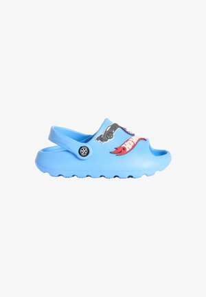 Sabot en caoutchouc bleu avec un motif de voiture, des flammes et le texte « Hot Wheels ». Dos ouvert, semelle texturée et trous de ventilation pour une meilleure respirabilité.
