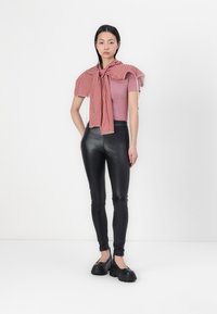 Fitted pink t-shirt with ruffled shoulders, red checkered scarf tied at the neck, black leather leggings, and chunky black shoes.