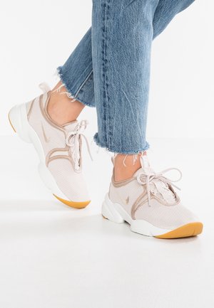 Jasnobeżowe siateczkowe sneakersy z białą i gumową podeszwą. Charakteryzują się zaokrąglonym kształtem, sznurowadłami z przodu oraz subtelnym detalem logo po boku.