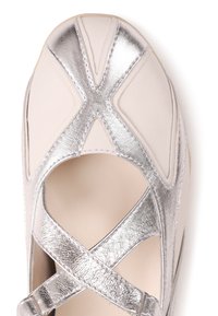 Δερμάτινο παπούτσι σε ανοιχτό κρεμ χρώμα με μεταλλικά ασημί λουράκια σε σχέδιο σταυρού, ανοιχτές πλευρές και στρογγυλεμένη μύτη. Λείο υφή και εμφανή ραμμένα διακοσμητικά στοιχεία.