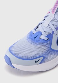 Ανοιχτό μπλε παπούτσι τρεξίματος με επάνω μέρος από δίχτυ, με σκούρο μπλε λογότυπο Nike, ομαλές λεπτομέρειες και μαλακή λευκή σόλα.