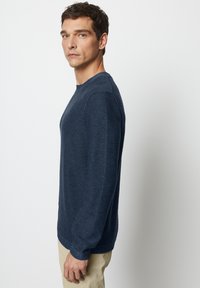 Dunkelblauer Strickpullover mit Rundhalsausschnitt und gerippten Saumabschlüssen. Die Textur ist mit einem gewebten Muster detailliert und bietet eine taillierte Silhouette.