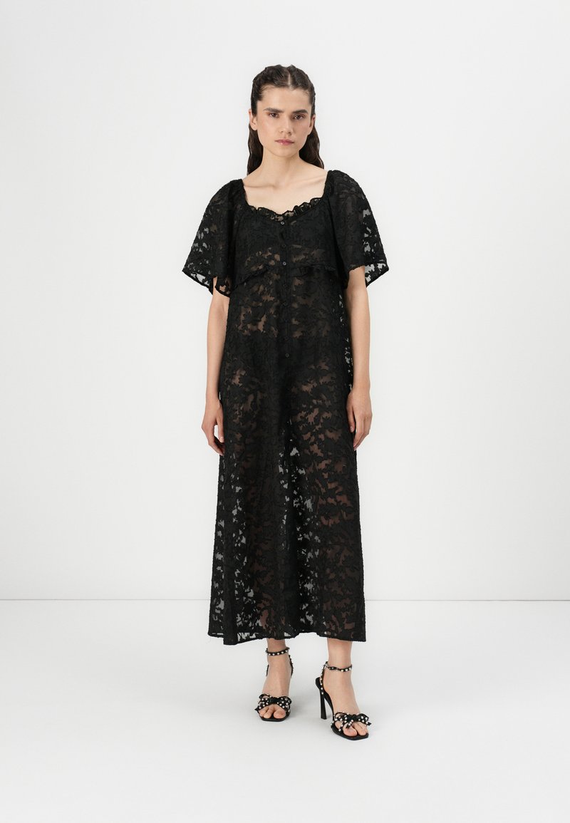 Black lace maxi dress with short sleeves, floral pattern, scoop neckline, and button details. Paired with black heeled sandals.
