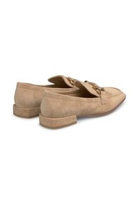 Beige suède instappers met een lage blokhak, voorzien van goudkleurige hardware en een gevouwen klepdesign; gladde textuur en minimale stiksels.