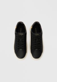 Černé kožené tenisky s plochými tkaničkami, bílou gumovou podrážkou a zlatými akcenty loga; vnitřek má květinový vzor na límci.