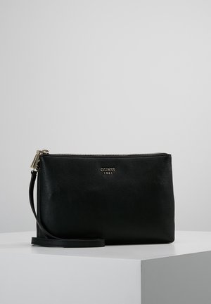 Czarna kopertówka GUESS na nadgarstek z srebrnym zamkiem i logo, prostokątny kształt, teksturowana skóra, pasek na nadgarstek na białej powierzchni.