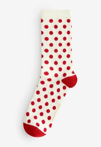 Białe skarpetki o prążkowanej fakturze, z wzorem czerwonych groszków i jednolitymi czerwonymi akcentami na palcach i ściągaczu.