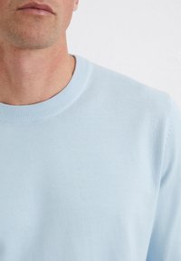 Jasnoniebieski sweter z dzianiny z prążkowanym okrągłym dekoltem. Miękka tekstura i dopasowany krój, idealny do codziennych stylizacji.