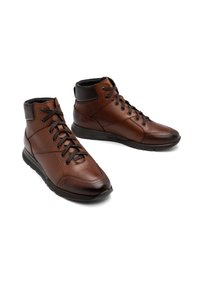 Brązowe skórzane sneakersy typu high-top z czarnymi akcentami, z okrągłymi sznurówkami, teksturowanym wierzchem i wyściełaną podeszwą dla komfortu.