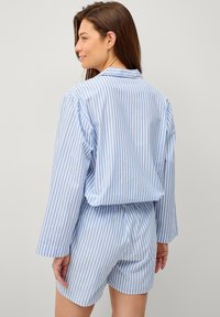 Lichtblauw en wit gestreept pyjamaSet met een lange mouwen knopen blouse en shorts, met een ontspannen pasvorm en zachte stoftextuur.