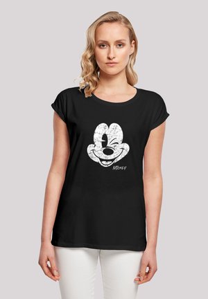 Schwarzes T-Shirt mit aufgerollten Ärmeln, das ein verwittertes weißes Grafikdesign von Mickey Mouses Gesicht und der Unterschrift am unteren Rand zeigt.