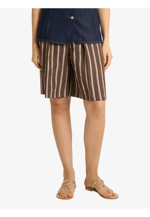 Persona che indossa pantaloncini marroni con strisce verticali bianche e rosa, un top blu scuro e sandali beige piatti.