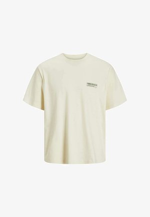 T-shirt en coton couleur crème, à manches courtes, col rond, arborant un petit logo vert "ORIGINALS" sur la partie gauche de la poitrine.